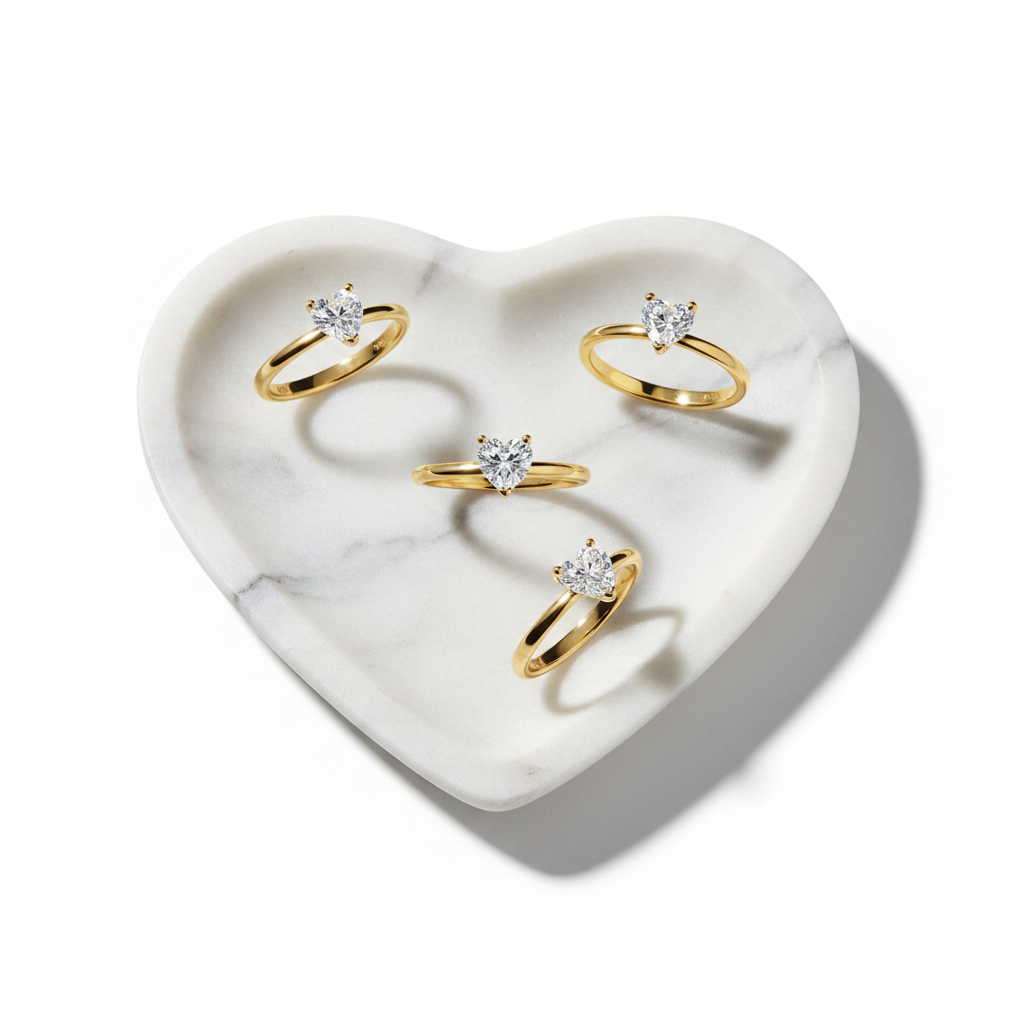 Set of gold rings with heart shape stone on a heart-shaped marble tray