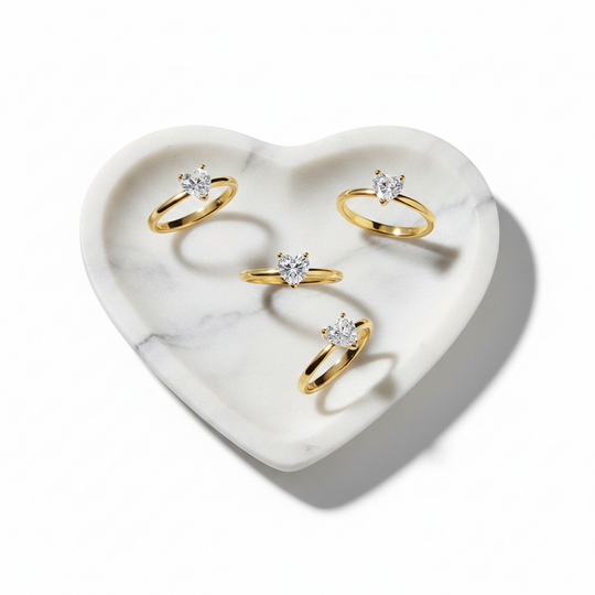 Set of gold rings with heart shape stone on a heart-shaped marble tray